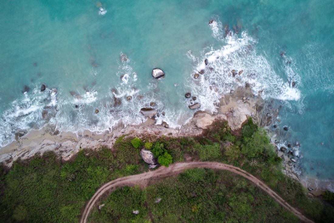 Aerial view of turquoise water breaking over a rocky tropical coast
